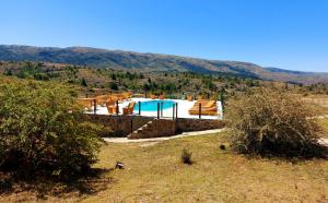 uma piscina num campo com montanhas ao fundo em Complejo Apus em La Cumbrecita