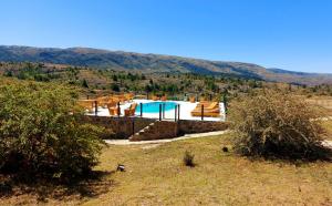 una piscina en un campo con montañas en el fondo en Complejo Apus en La Cumbrecita