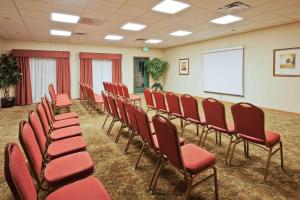 Country Inn & Suites by Radisson, Jacksonville West, FL في جاكسونفيل: قاعة المؤتمرات ذات الكراسي الحمراء والشاشة البيضاء