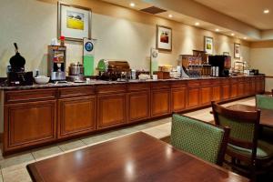 Country Inn & Suites by Radisson, Jacksonville West, FL في جاكسونفيل: مطعم فيه بار فيه دواليب خشبية وطاولات