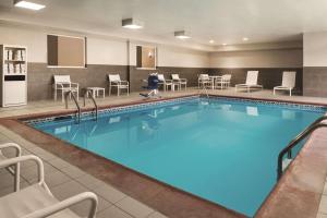 una piscina en una habitación de hotel con sillas y mesas en Country Inn & Suites by Radisson, Indianapolis South, IN, en Indianápolis