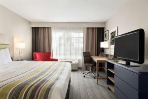 a hotel room with a bed and a desk with a television at Country Inn & Suites by Radisson, Romeoville, IL in Romeoville