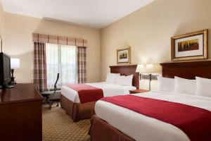 a hotel room with two beds and a desk at Country Inn & Suites by Radisson, Macon North, GA in Macon