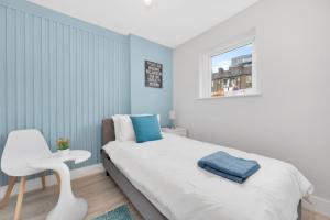 ein Schlafzimmer mit einem weißen Bett und einem weißen Stuhl in der Unterkunft Waterside 4 Bed Apartment in London