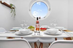 ein weißes Esszimmer mit einem Tisch und einer Flasche Wein in der Unterkunft Waterside 4 Bed Apartment in London