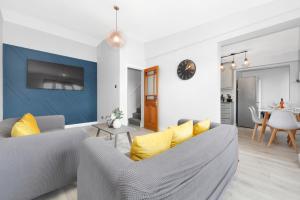 ein Wohnzimmer mit einem grauen Sofa und gelben Kissen in der Unterkunft Waterside 4 Bed Apartment in London