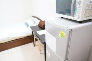 eine Mikrowelle auf einem Kühlschrank im Zimmer in der Unterkunft 難波南51 in Osaka