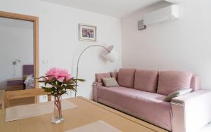 a living room with a pink couch and a table at Apartments Lila in Cres