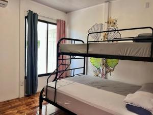 two bunk beds in a room with a window at La Tribu Boutique Hostel for women in Puerto Viejo