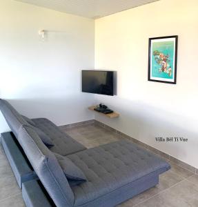 um sofá numa sala de estar com uma televisão de ecrã plano em Villa Bèl Ti Vue Piscine Vue Mer et Montagne Pelée em Le Carbet