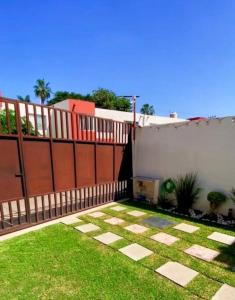 einen Hinterhof mit einem Zaun und einem Garten mit Gras in der Unterkunft Casa Mandala Reload Cuerna in Cuernavaca