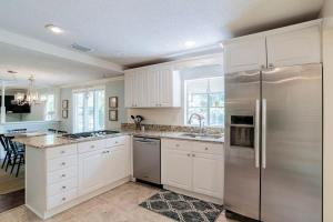 a kitchen with white cabinets and a stainless steel refrigerator at Dozing on Dog River- River Access Dock Yard in Tillmans Corner