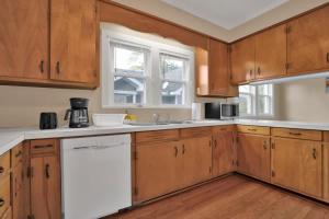 a kitchen with wooden cabinets and a white dishwasher at Crafty in Haymount- Mins to Downtown Fayetteville! in Fayetteville