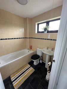 a bathroom with a tub and a toilet and a sink at Homely Milton Keynes Stay! in Milton Keynes