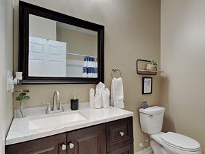een badkamer met een wastafel, een toilet en een spiegel bij Rockaway Rookwood Retreat- Unit 1 in Indianapolis