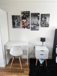 una scrivania in una stanza con una sedia e immagini appese al muro di Luxury Hotel Rooms a Palmers Green