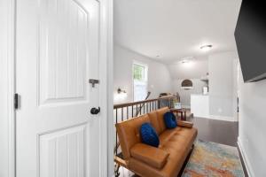 uma sala de estar com um sofá de couro castanho com almofadas azuis em The Campbell Carriage House em Clarksville