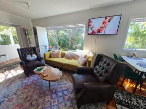 ein Wohnzimmer mit einem Sofa, Stühlen und einem Tisch in der Unterkunft Paris studio in Auckland