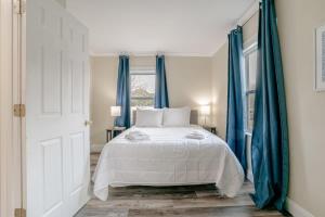 1 dormitorio con cama blanca y cortinas azules en Our Place on Potter, en Mobile