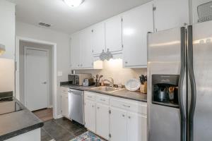 a kitchen with white cabinets and a stainless steel refrigerator at Enchanting Forestwood Retreat in Mobile