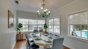 a dining room with a table and chairs and windows at Flamingle in Fushia- Unit A- Steps to the Beach! in Tybee Island