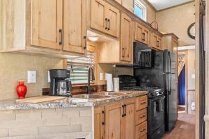 a kitchen with wooden cabinets and a black refrigerator at Big-Tiny Home Farm Stay-15Min to Chattanooga in Wildwood