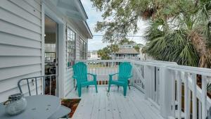 a porch with two chairs and a table on it at Flamingle in Fushia- Unit A- Steps to the Beach! in Tybee Island