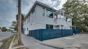 a white house with a blue fence on a street at Flamingle in Fushia- Unit B- Steps to the Beach! in Tybee Island