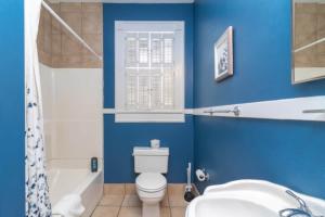 a blue bathroom with a toilet and a tub and a sink at The Parkside Cottage Lakebottom Park at Doorstep! in Columbus