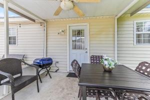 a patio with a table and chairs and a ceiling fan at Screened Porch Firepit Patio Peaceful in Pooler in Savannah
