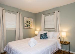 a bedroom with a white bed with two windows at Mins to Zoo Hospital & UA - Broadmoor Bungalow in Little Rock