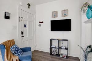 sala de estar con sofá azul y TV de pantalla plana en Charming Midtown Apt - Hannon Hideaway Unit A en Mobile