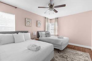 a bedroom with two beds and a ceiling fan at 10 Mins to Legion Field Stadium- Blushing Bungalow in Birmingham