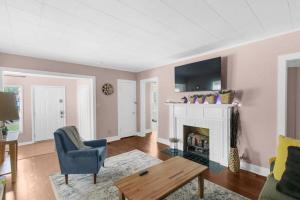 a living room with a fireplace and a blue chair at 10 Mins to Legion Field Stadium- Blushing Bungalow in Birmingham