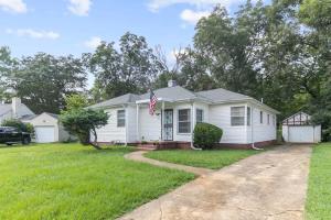 a white house with a flag in the yard at 10 Mins to Legion Field Stadium- Blushing Bungalow in Birmingham