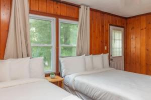 2 letti in una camera da letto con pareti e finestre in legno di Near Benning w Fenced Yard- Family Ranch Retreat a Columbus