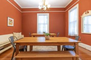 a dining room with orange walls and a wooden table and chairs at Goldfinch Mansion Historic Luxury on the Park in Columbus