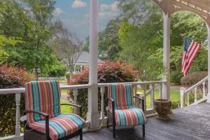 zwei Stühle auf einer Veranda mit einer amerikanischen Flagge in der Unterkunft Goldfinch Mansion Historic Luxury on the Park in Columbus