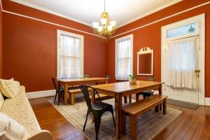 une salle à manger avec des murs orange et des tables et des chaises en bois dans l'établissement Bumblebee Mansion w Tiny Home Historic Modern, à Columbus