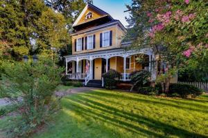 ein gelbes Haus mit einer Veranda und einem Hof in der Unterkunft Bumblebee Mansion w Tiny Home Historic Modern in Columbus + 152 Fotos