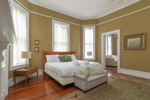 a bedroom with a bed and a chair and windows at Goldfinch Mansion Historic Luxury on the Park in Columbus