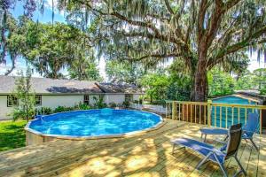 a swimming pool with chairs and a tree at Studio with Gazebo-Swanky Savannah Style in Savannah