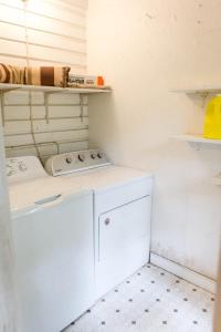 uma lavandaria branca com máquina de lavar e secar roupa em The Historic Cottage Screened Porch & Hammock em Columbia