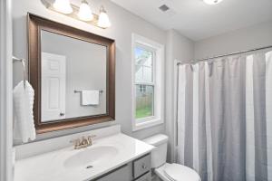 ein Badezimmer mit einem Waschbecken, einem WC und einem Spiegel in der Unterkunft The Navy Nestler Bright & Stylish Near Downtown in Clarksville