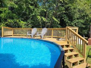 a swimming pool with two chairs next to a wooden deck at Midcentury Modern - Pool & Hot tub - Retro Retreat in Mobile