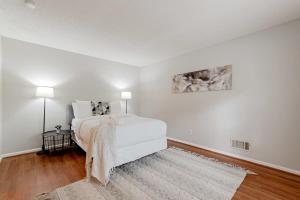 a white bedroom with a bed and a rug at Soda City Suite in Columbia