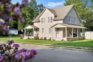 una casa bianca con fiori viola di fronte di The Heart of Merrimack Historic Mansion a Huntsville