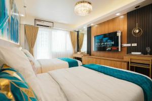 a hotel room with two beds and a flat screen tv at Hawaii Suite by Guest Reservations Manila in Manila