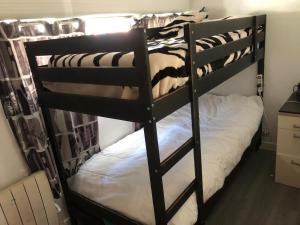 a black bunk bed in a room with a white bed at Appartement avec terrasse in Saint-Ouen