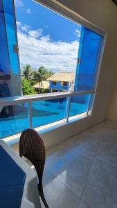 Un balcón con una silla y vistas al océano. en Flats Bahia, en Coruripe